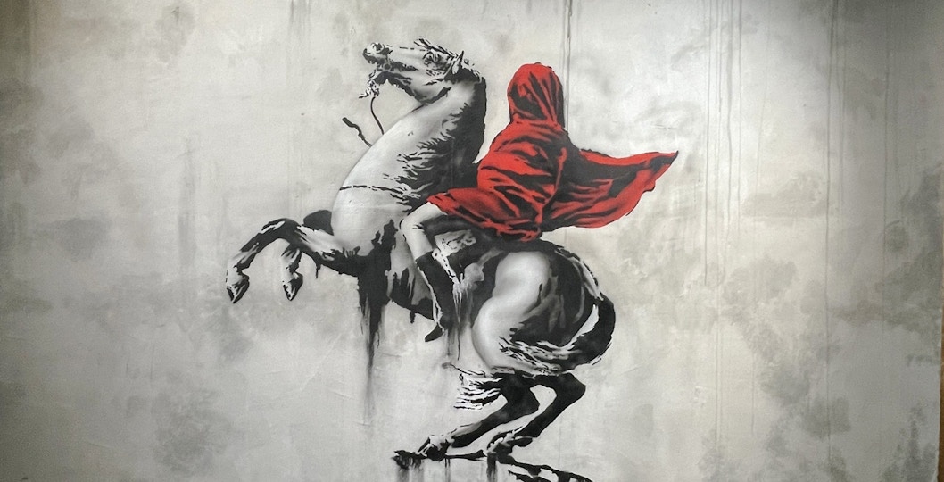 Street art of a hooded figure on a rearing horse at Banksy Museum, Amsterdam.