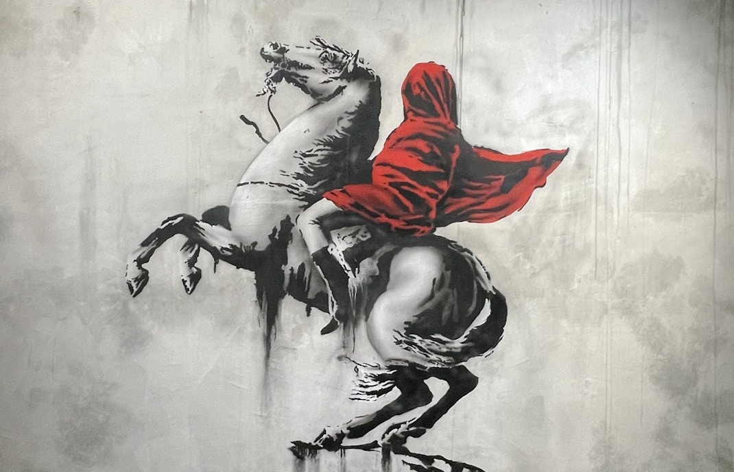 Street art of a hooded figure on a rearing horse at Banksy Museum, Amsterdam.