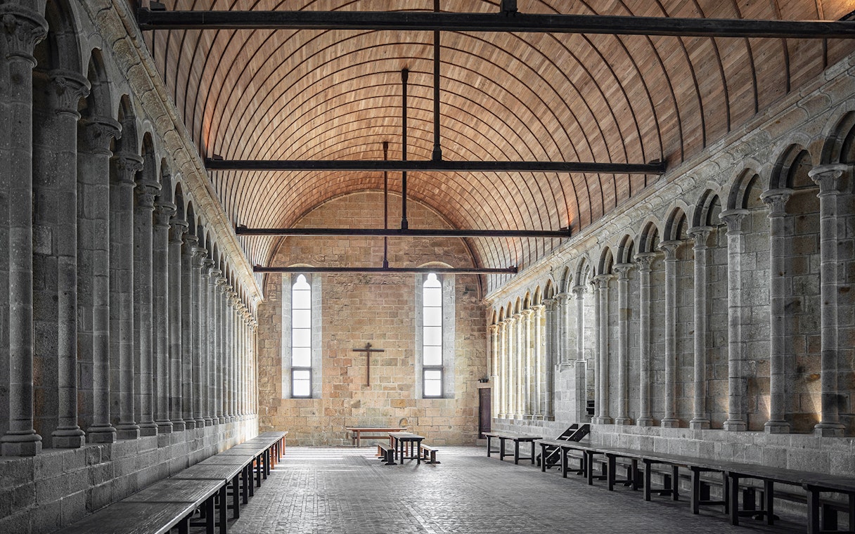 Interior of Mont Saint Michel Abbey with stone columns and arched ceiling.