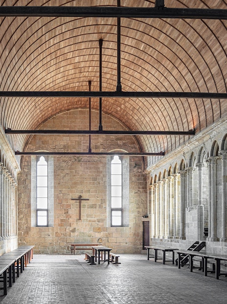 Interior of Mont Saint Michel Abbey with stone columns and arched ceiling.