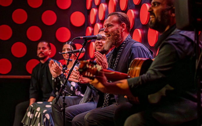 Flamenco performers clapping and playing guitar at Los Tarantos show.