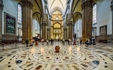 Interior view of Florence Cathedral with ornate marble floor and stained glass windows.