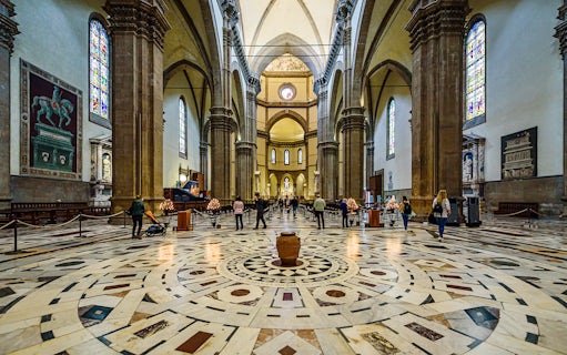 Interior view of Florence Cathedral with ornate marble floor and stained glass windows.