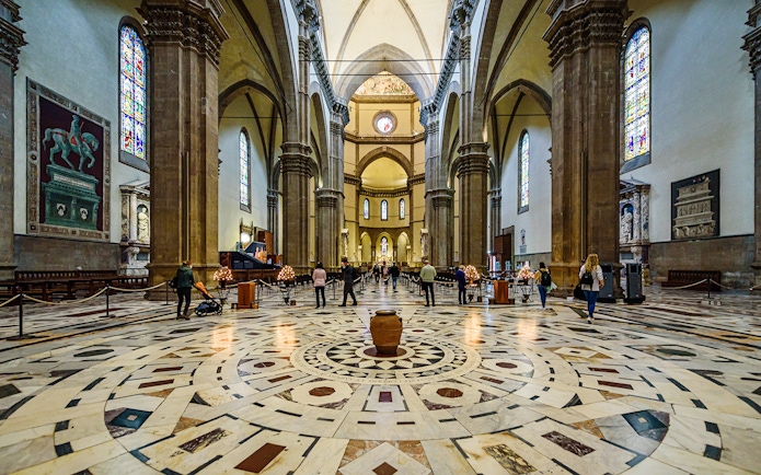 Interior view of Florence Cathedral with ornate marble floor and stained glass windows.