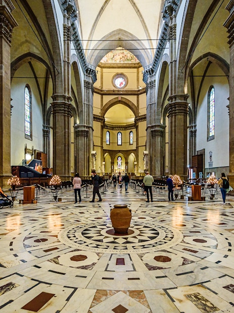 Interior view of Florence Cathedral with ornate marble floor and stained glass windows.