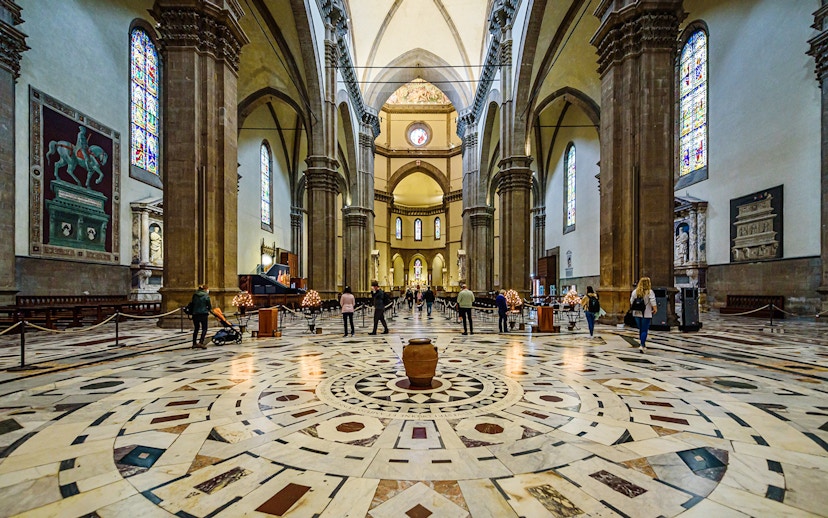 Interior view of Florence Cathedral with ornate marble floor and stained glass windows.