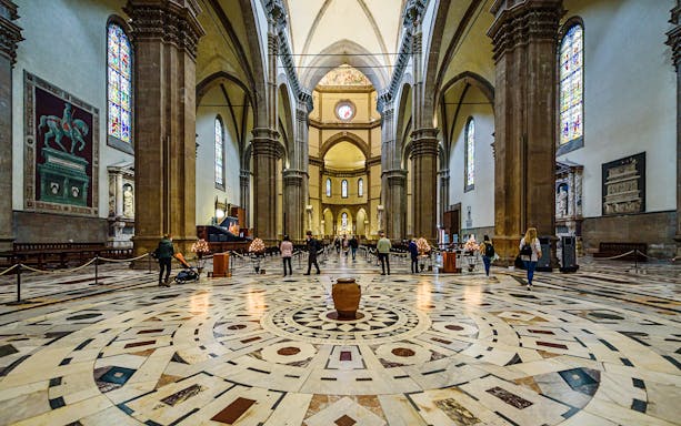 Interior view of Florence Cathedral with ornate marble floor and stained glass windows.