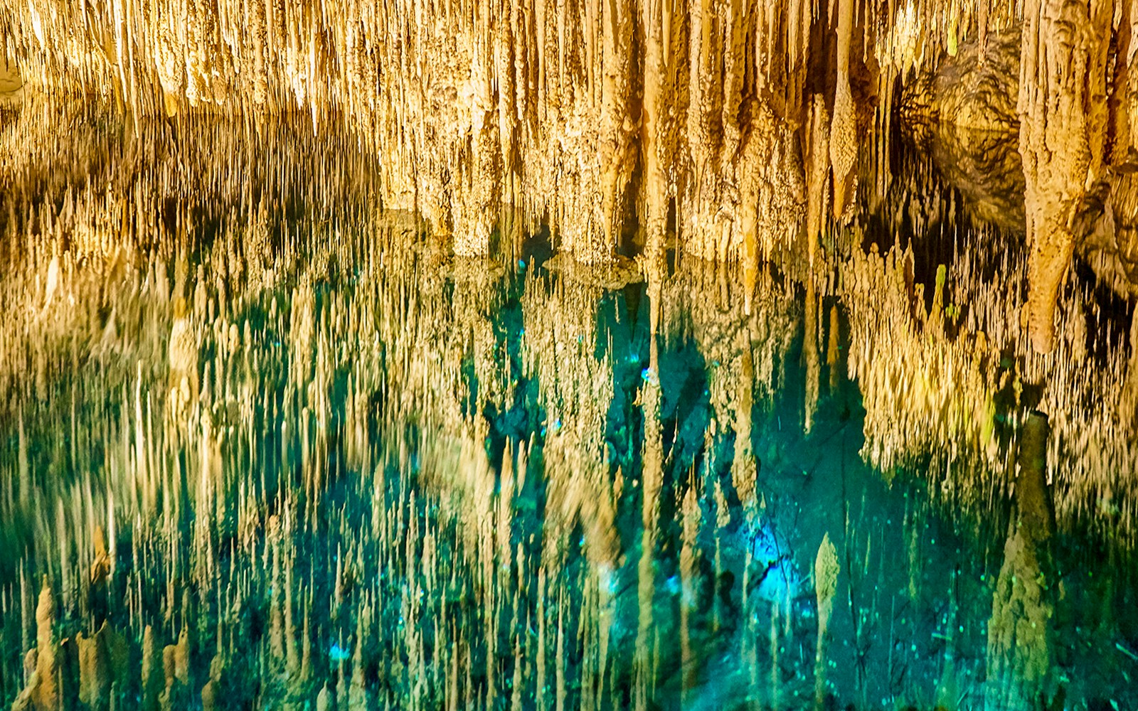 Stalactites reflecting in the turquoise waters of Cave of the Bells, Drach Caves, Mallorca.
