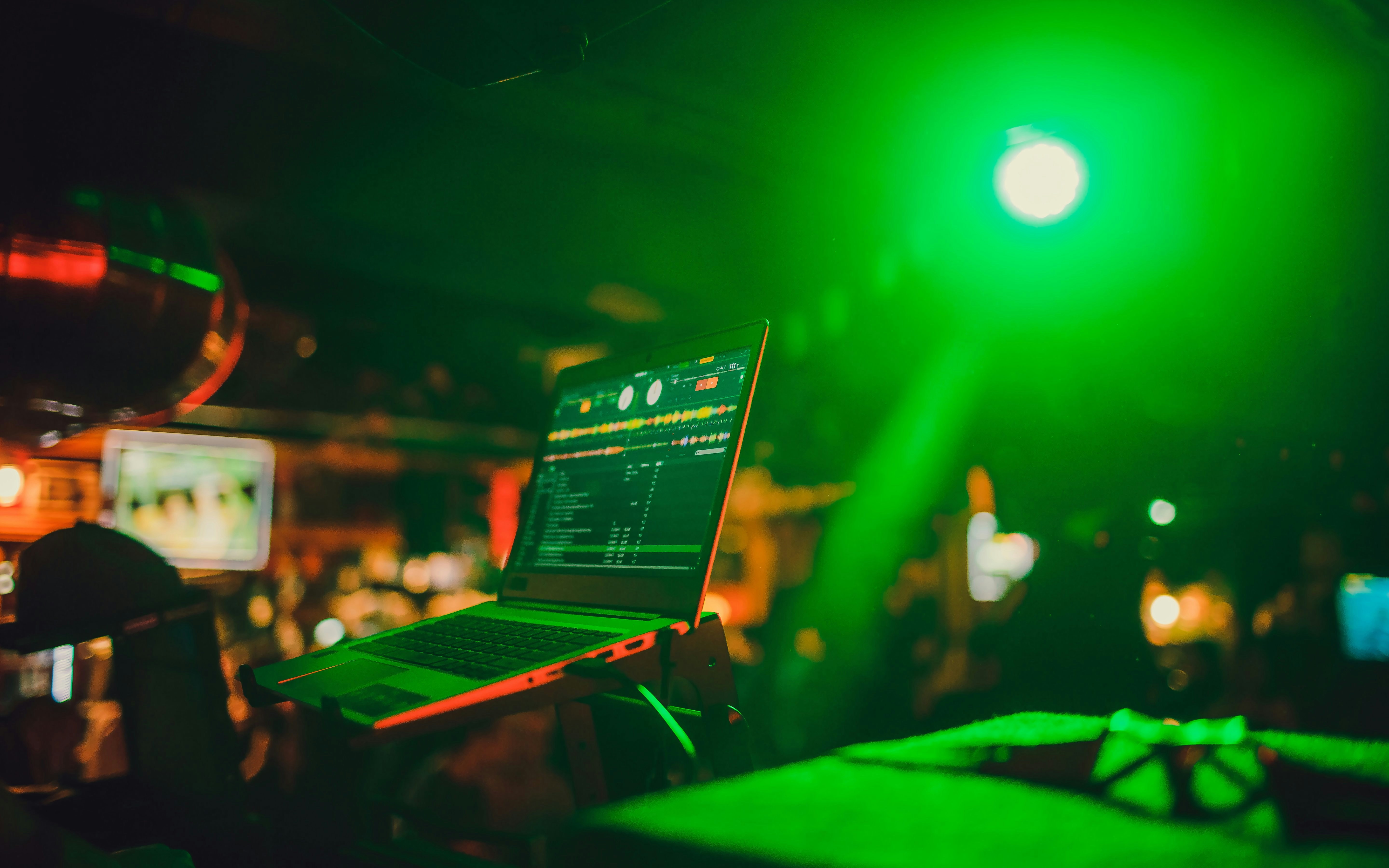 DJ mixing tracks on a laptop in a vibrant nightclub setting.