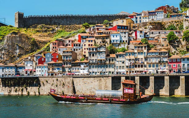 Tourist boat ride along Porto's colorful riverside buildings and historic city wall.