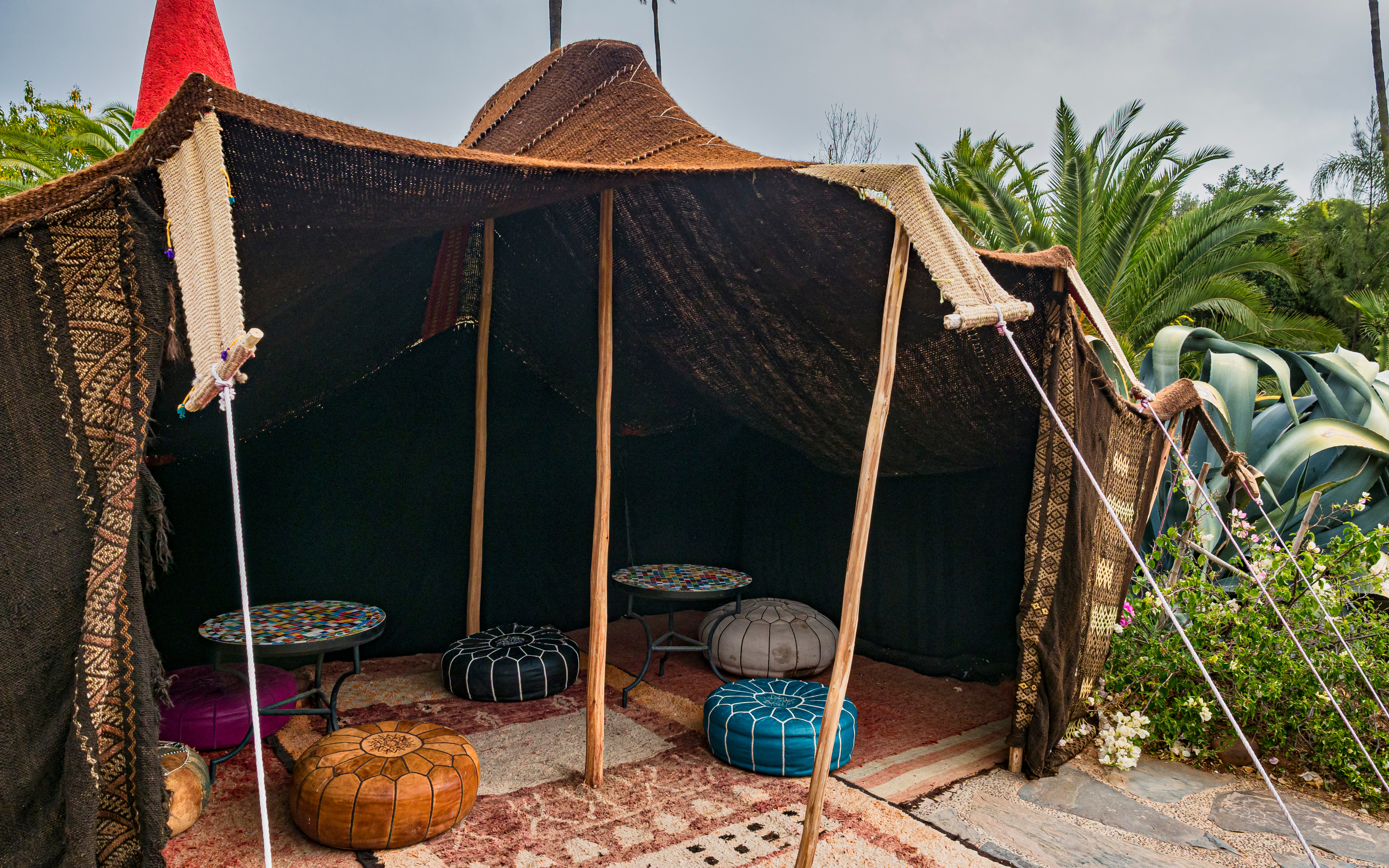 Traditional Moroccan tent with colorful poufs and tables at ANIMA Garden.