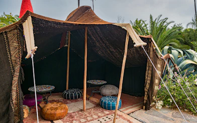 Traditional Moroccan tent with colorful poufs and tables at ANIMA Garden.
