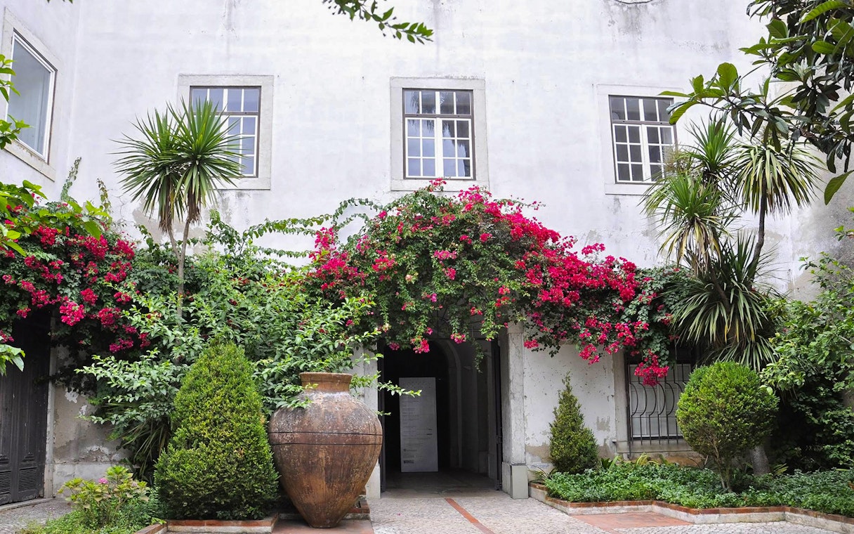 National Tile Museum courtyard with lush greenery and vibrant flowers, Lisbon.