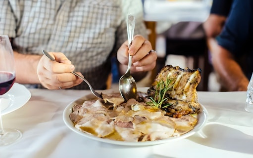 Person enjoying traditional Tuscan dish with wine during cooking class in countryside.