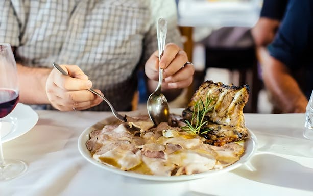Person enjoying traditional Tuscan dish with wine during cooking class in countryside.