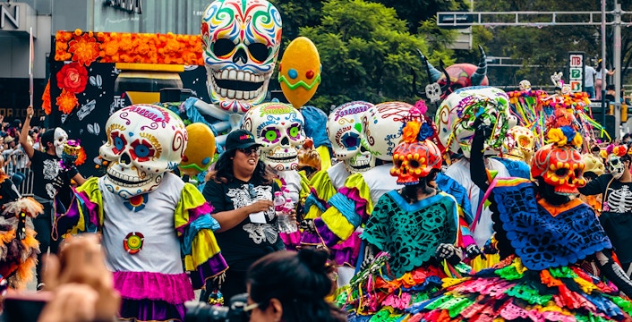 Colorful Day of the Dead parade with participants in skull costumes, Mexico City.