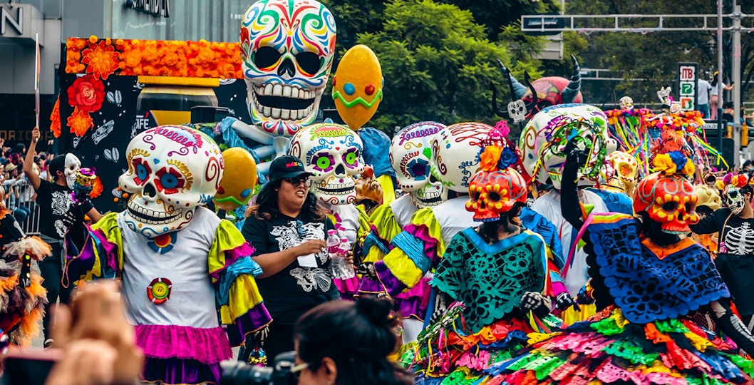 Colorful Day of the Dead parade with participants in skull costumes, Mexico City.