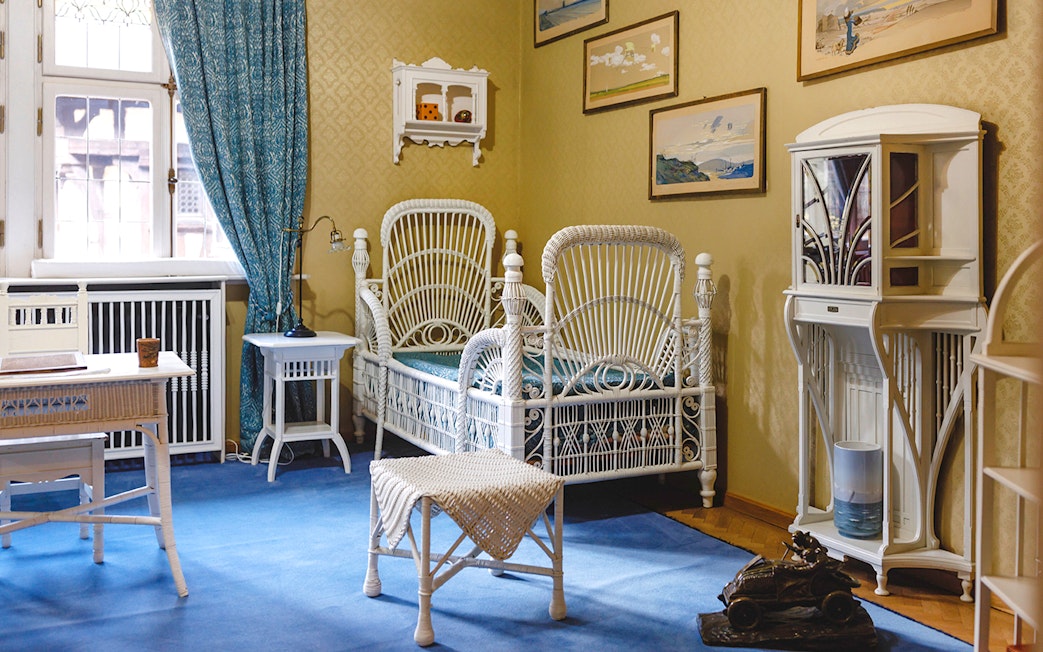 Luxurious room with wicker bed, desk, chairs, and bookshelf at Peles Castle.