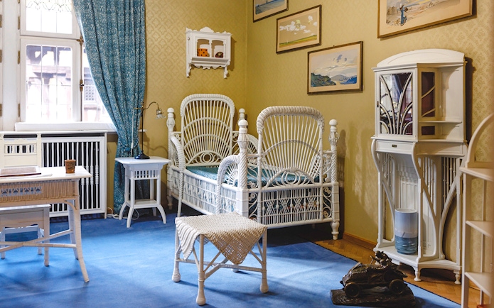 Luxurious room with wicker bed, desk, chairs, and bookshelf at Peles Castle.