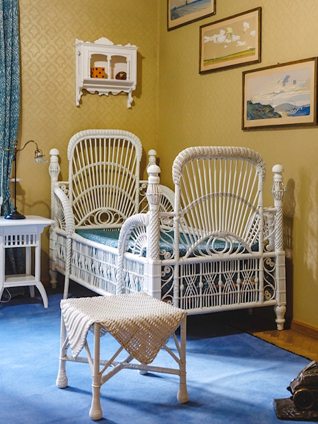 Luxurious room with wicker bed, desk, chairs, and bookshelf at Peles Castle.