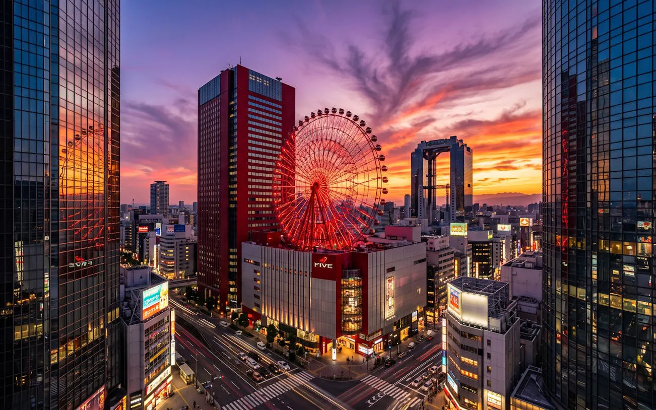 Ferris wheel and cityscape at sunset in Osaka's Umeda district.
