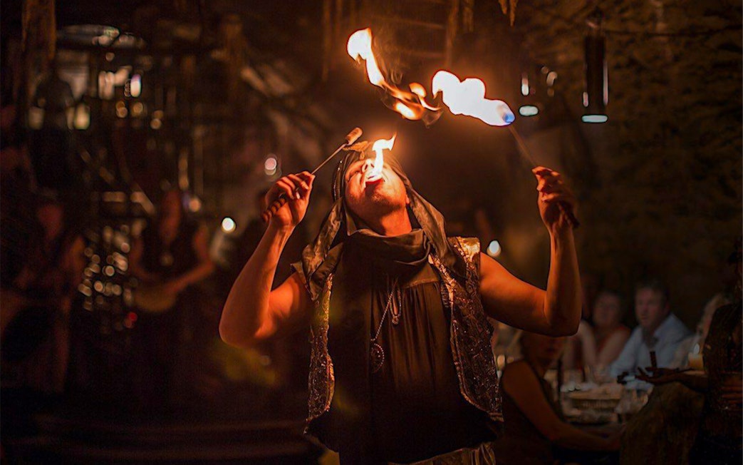 Fire performer at a medieval dinner show entertaining guests with fire-eating act.