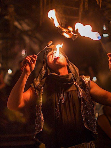 Fire performer at a medieval dinner show entertaining guests with fire-eating act.