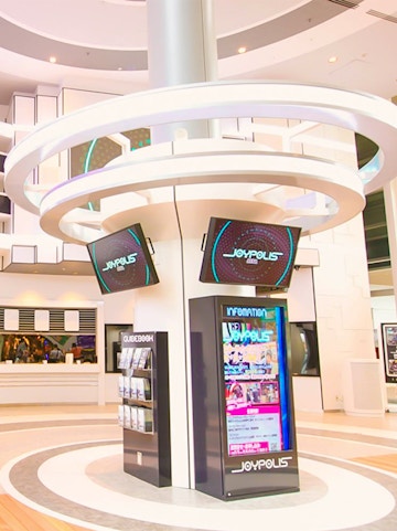 Joypolis information kiosk with digital screens in a modern indoor setting.