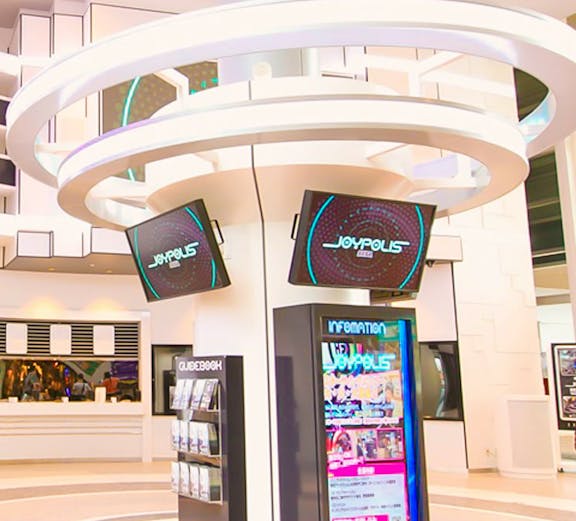 Joypolis information kiosk with digital screens in a modern indoor setting.