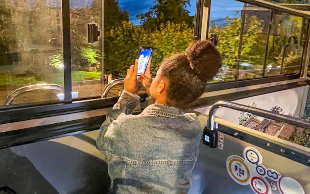 Person taking a photo from a bus window in Brussels before nightfall.