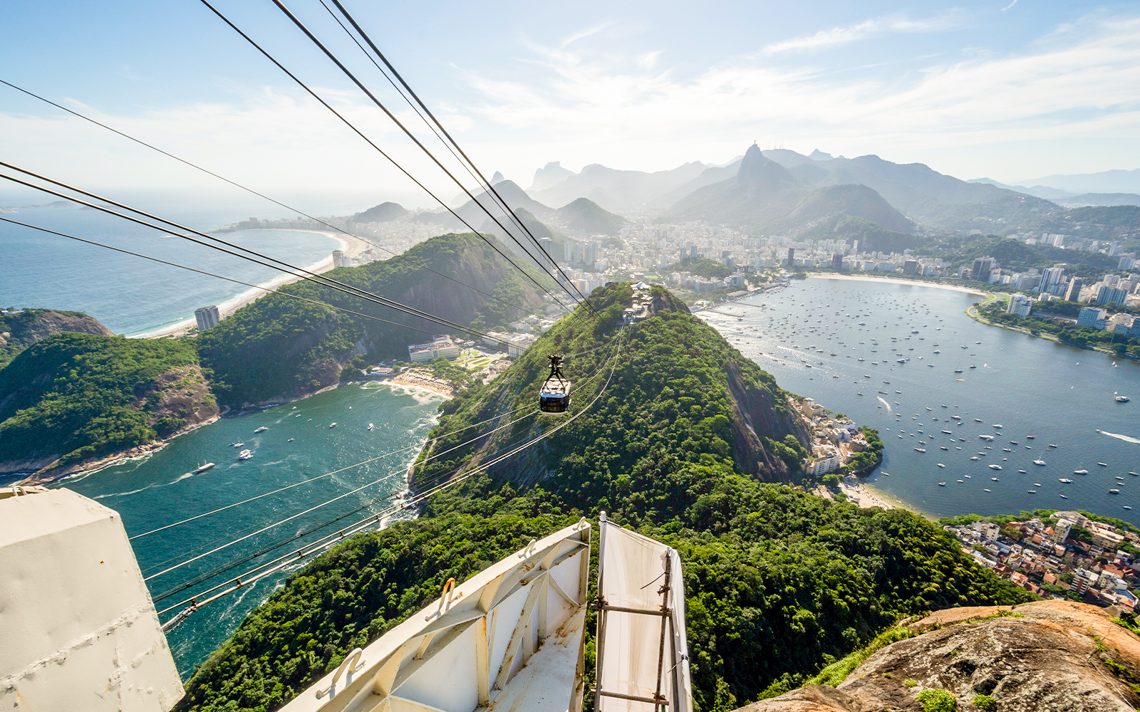 Cable car ascending Sugar Loaf Mountain with Rio de Janeiro city and ocean view.