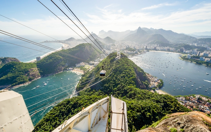 Cable car ascending Sugar Loaf Mountain with Rio de Janeiro city and ocean view.