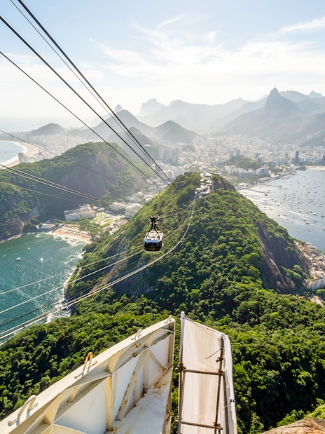 Cable car ascending Sugar Loaf Mountain with Rio de Janeiro city and ocean view.