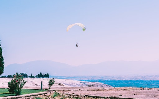 Tandem paragliding over Pamukkale's travertine terraces and landscape.