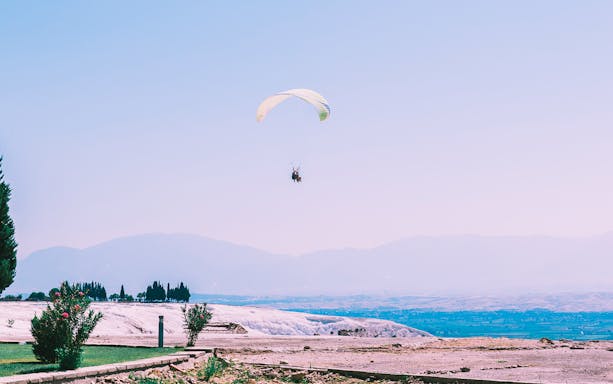Tandem paragliding over Pamukkale's travertine terraces and landscape.