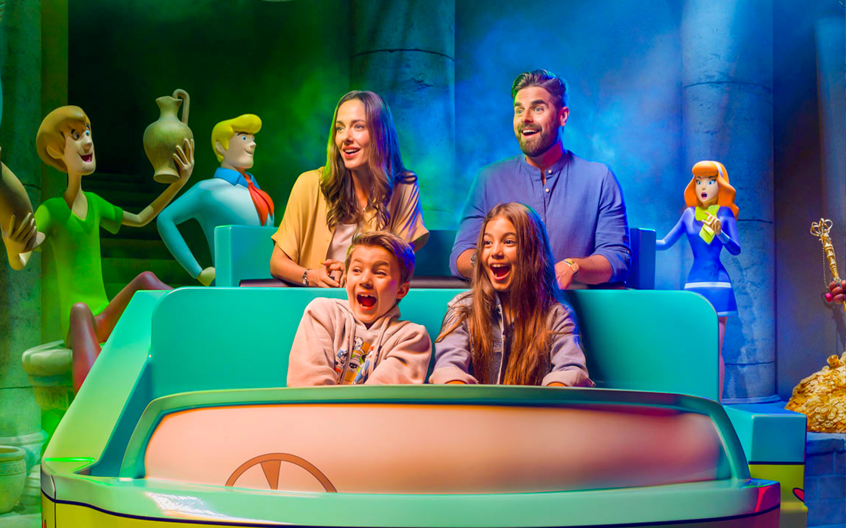Visitors on a ride at Warner Bros. theme park, Yas Island, Abu Dhabi, surrounded by cartoon characters.