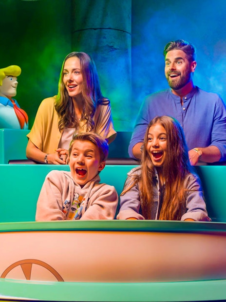 Visitors on a ride at Warner Bros. theme park, Yas Island, Abu Dhabi, surrounded by cartoon characters.