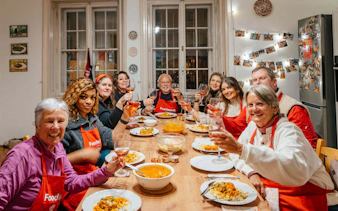 Guests enjoying a Hungarian cooking class in Budapest, toasting with wine around a dining table.