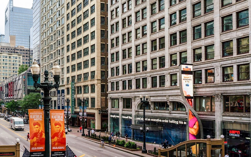 Street view of ABC Building in Chicago with pedestrians and nearby shops.