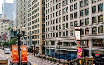 Street view of ABC Building in Chicago with pedestrians and nearby shops.