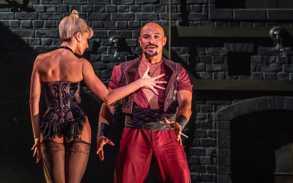 Performers on stage during Moulin Rouge! The Musical, with a dramatic brick backdrop.