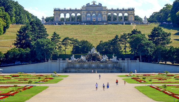 Gloriette pavilion in Schönbrunn garden, Vienna, with visitors and landscaped grounds.