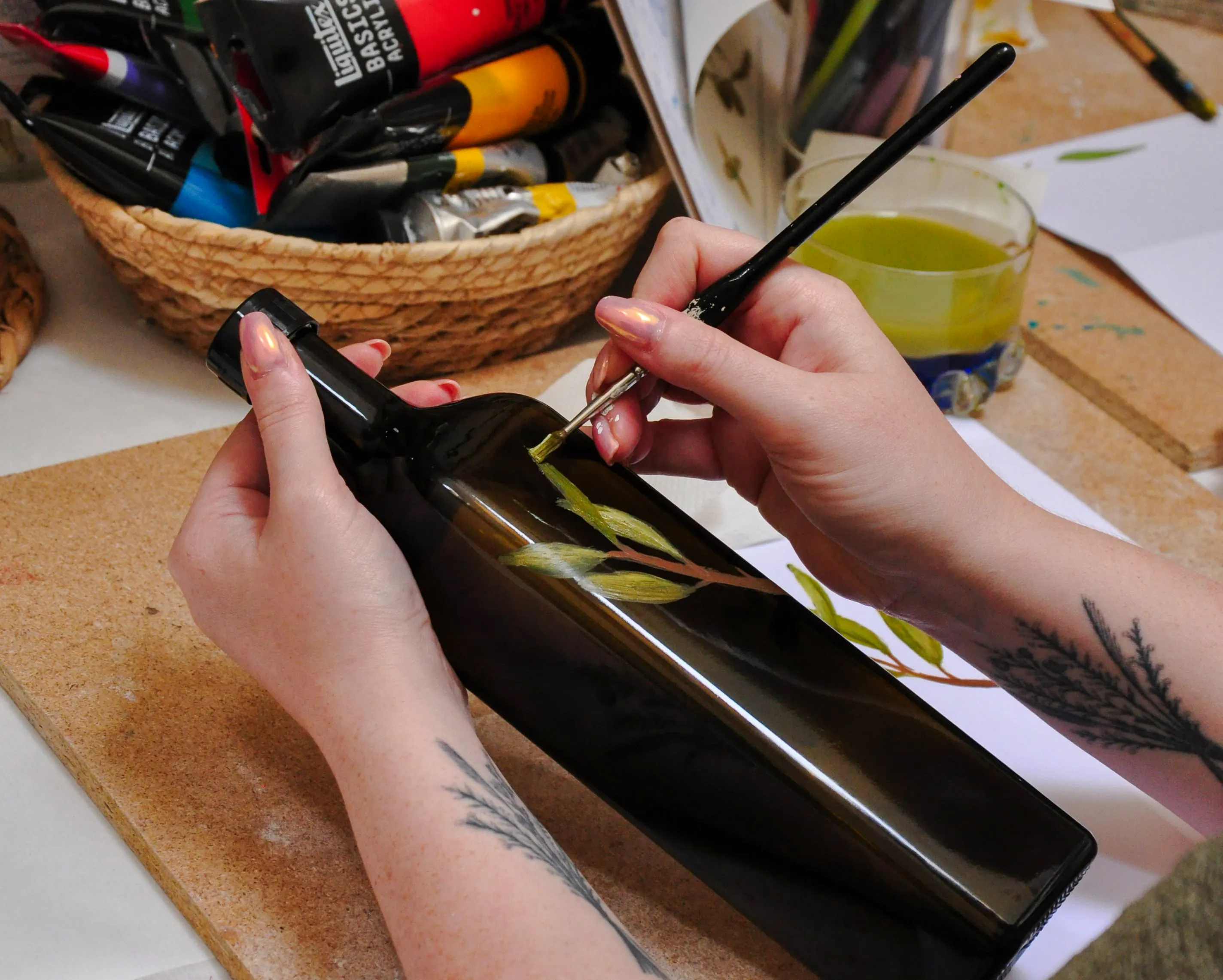Painting olive branches on a bottle during an Athens olive oil workshop.