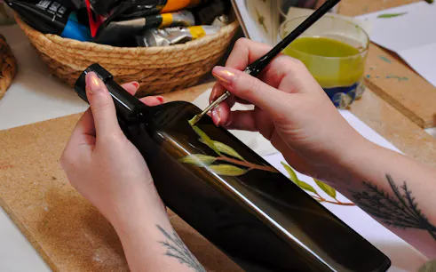 Painting olive branches on a bottle during an Athens olive oil workshop.