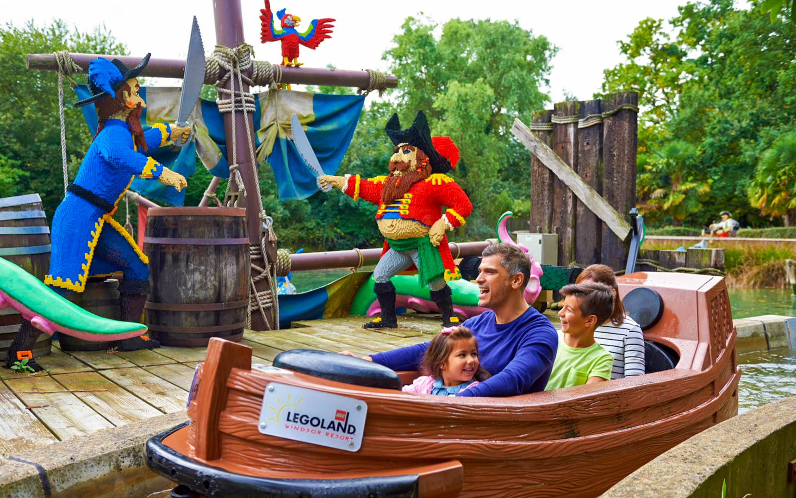 Family enjoying a boat ride past LEGO pirate figures at LEGOLAND Windsor Resort.