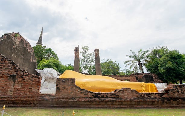 Reclining Buddha statue covered in yellow cloth at Ayutthaya temple, Thailand.