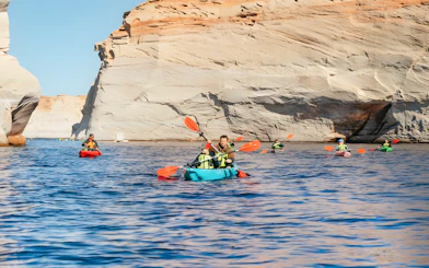 Kayakers paddling on Lake Powell near Antelope Canyon's sandstone cliffs.