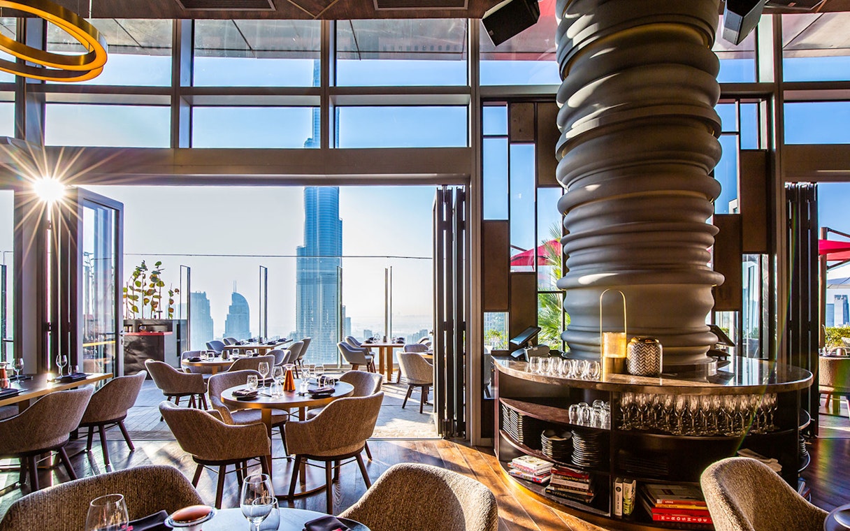 Dining area at CÉ LA VI Dubai with Burj Khalifa view through large windows.