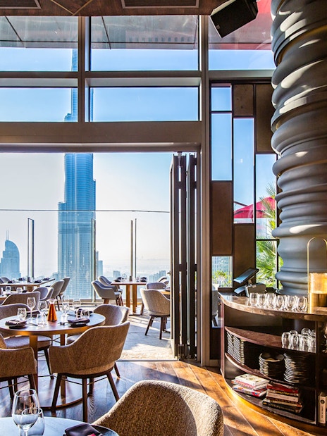 Dining area at CÉ LA VI Dubai with Burj Khalifa view through large windows.