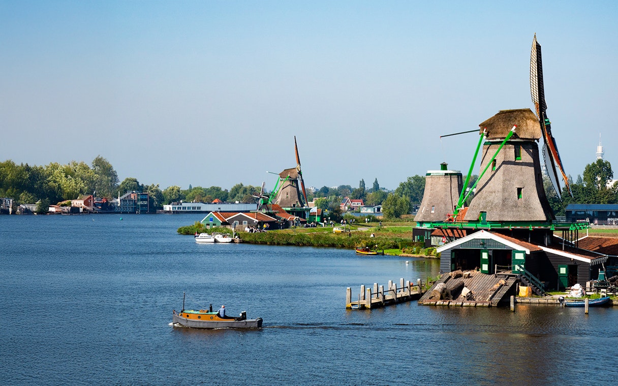Zaanse Schans windmills and boat on the river near Amsterdam.